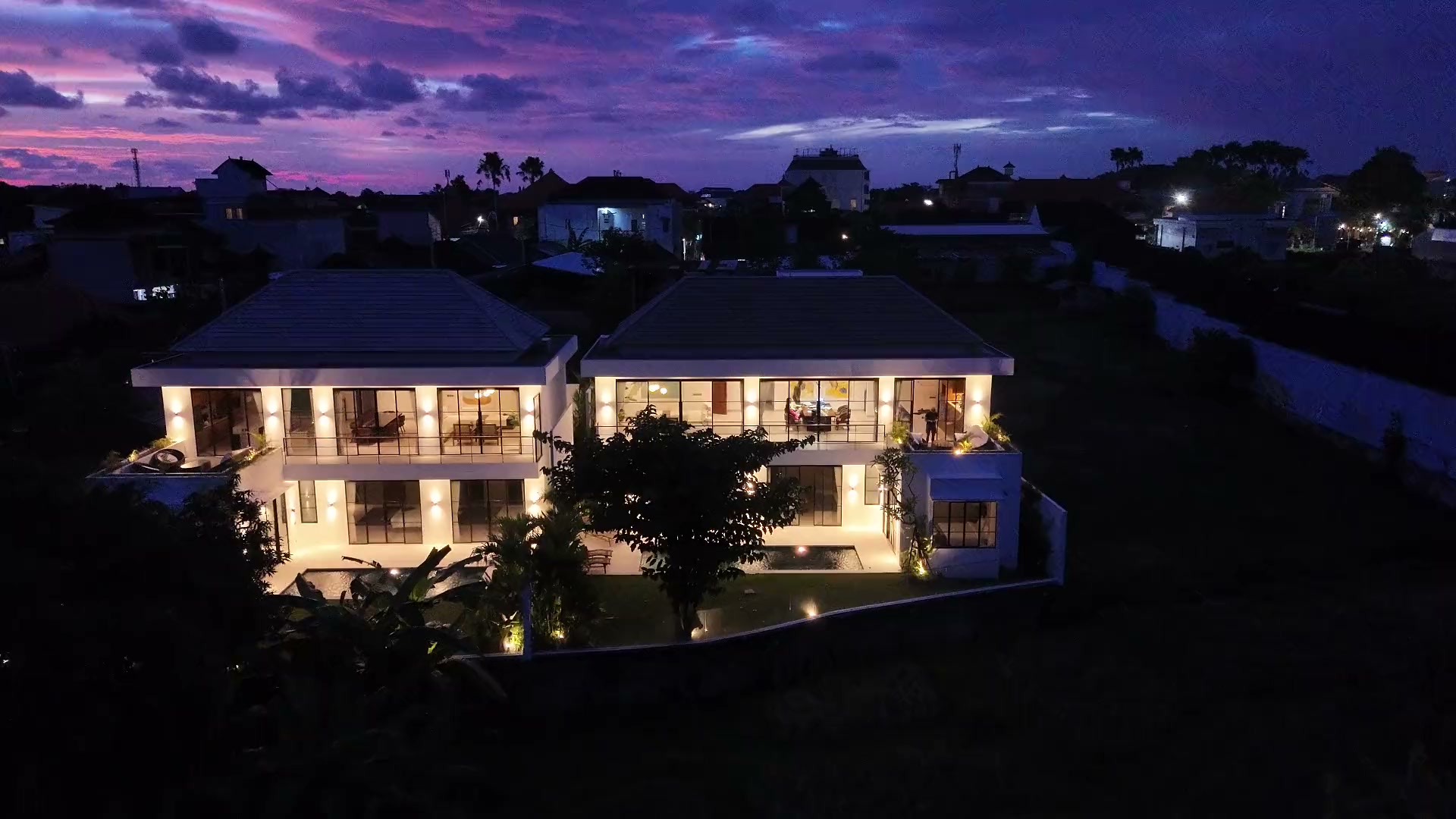 Aerial view of Villa Rice at dusk, both villas lit over the rice field